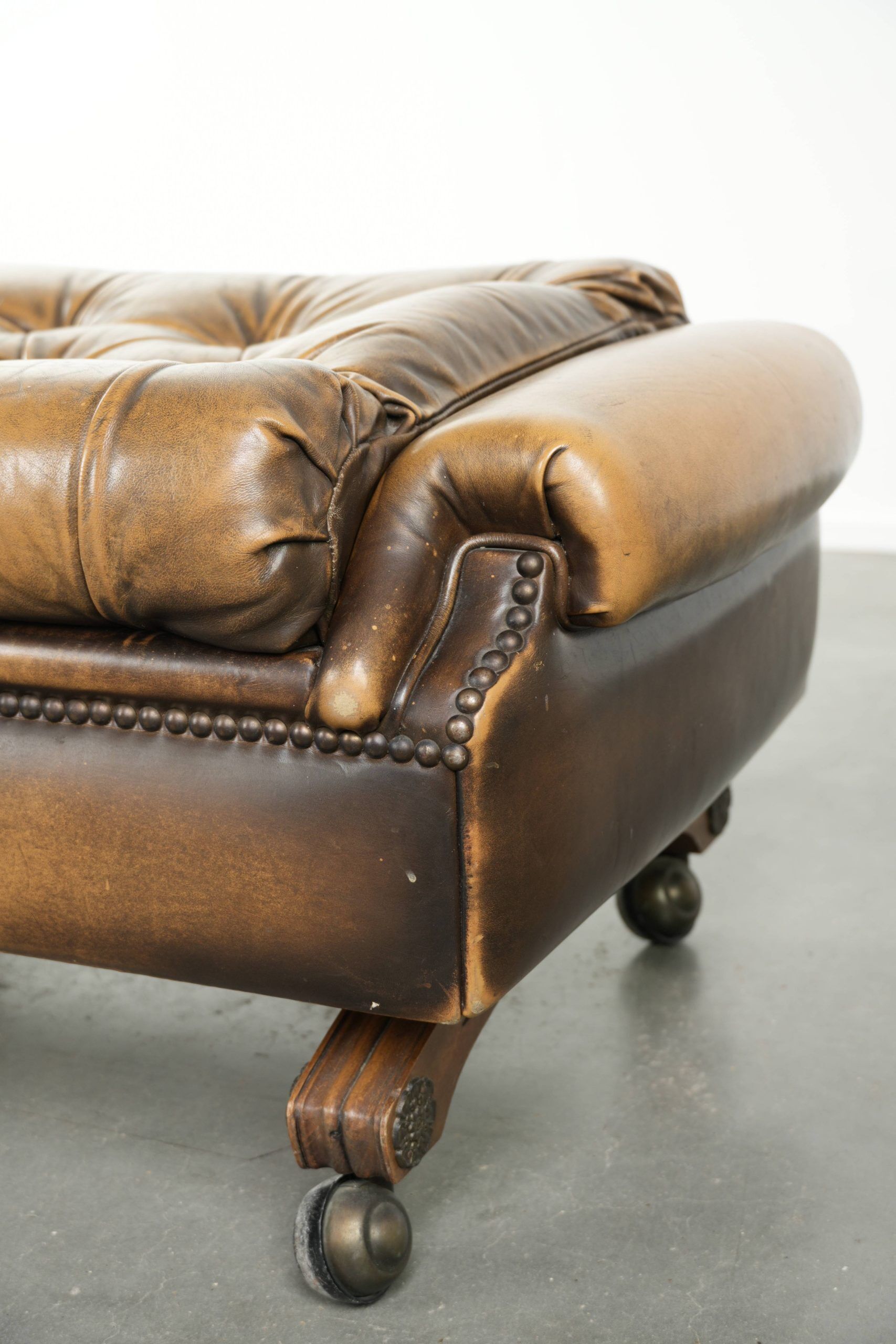 Ottoman chesterfield anglais en cuir élégant, fini avec des clous décoratifs.