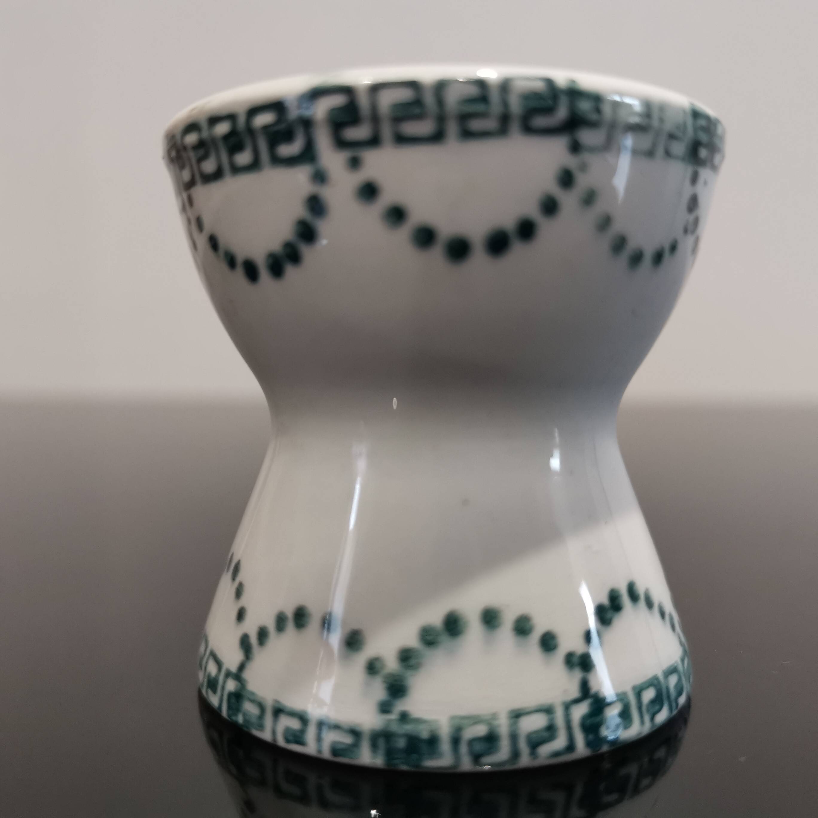 Old porcelain diabolo egg cup decorated with green frieze and garlands