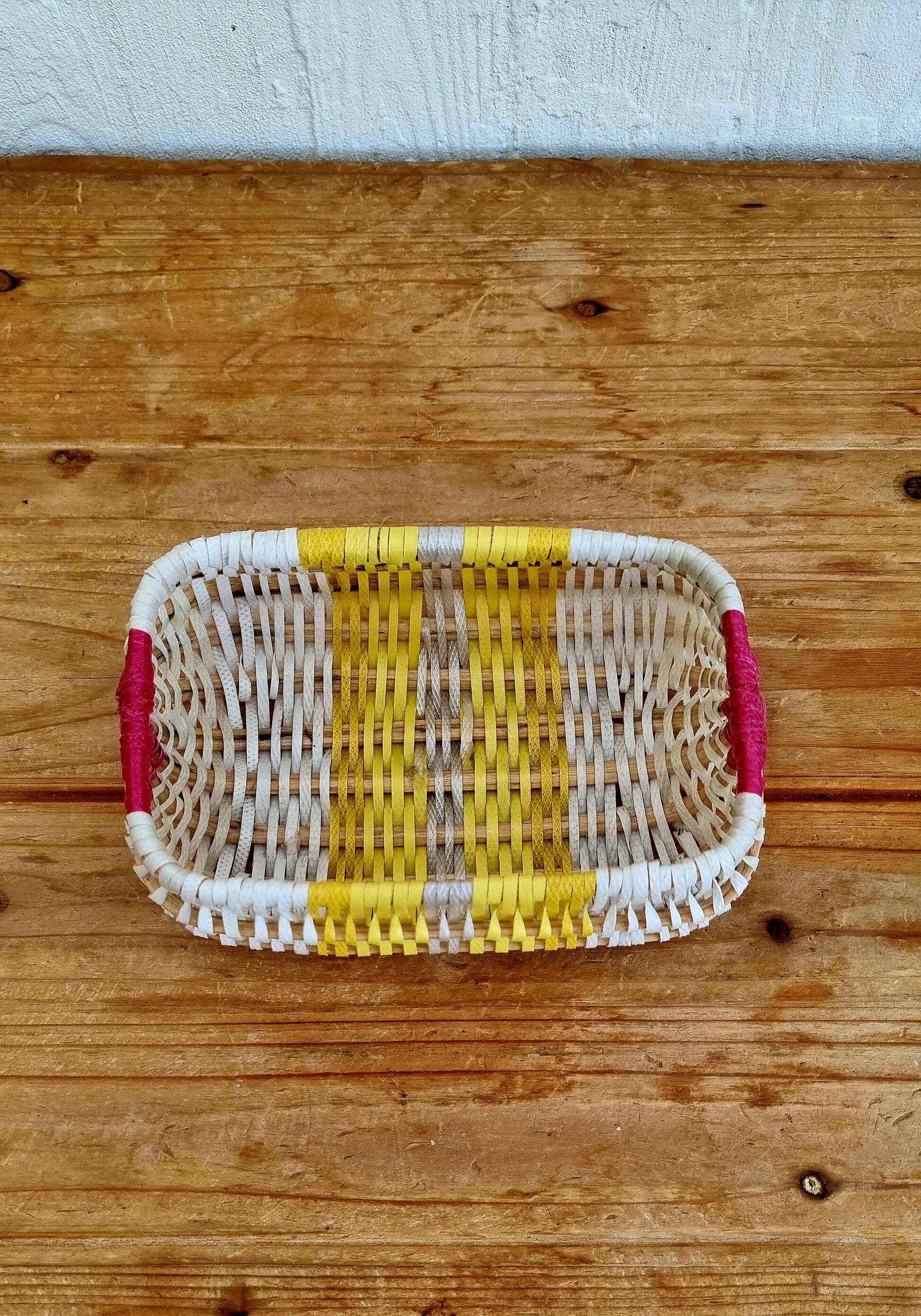 Vintage woven basket in yellow, white, and pink plastic.