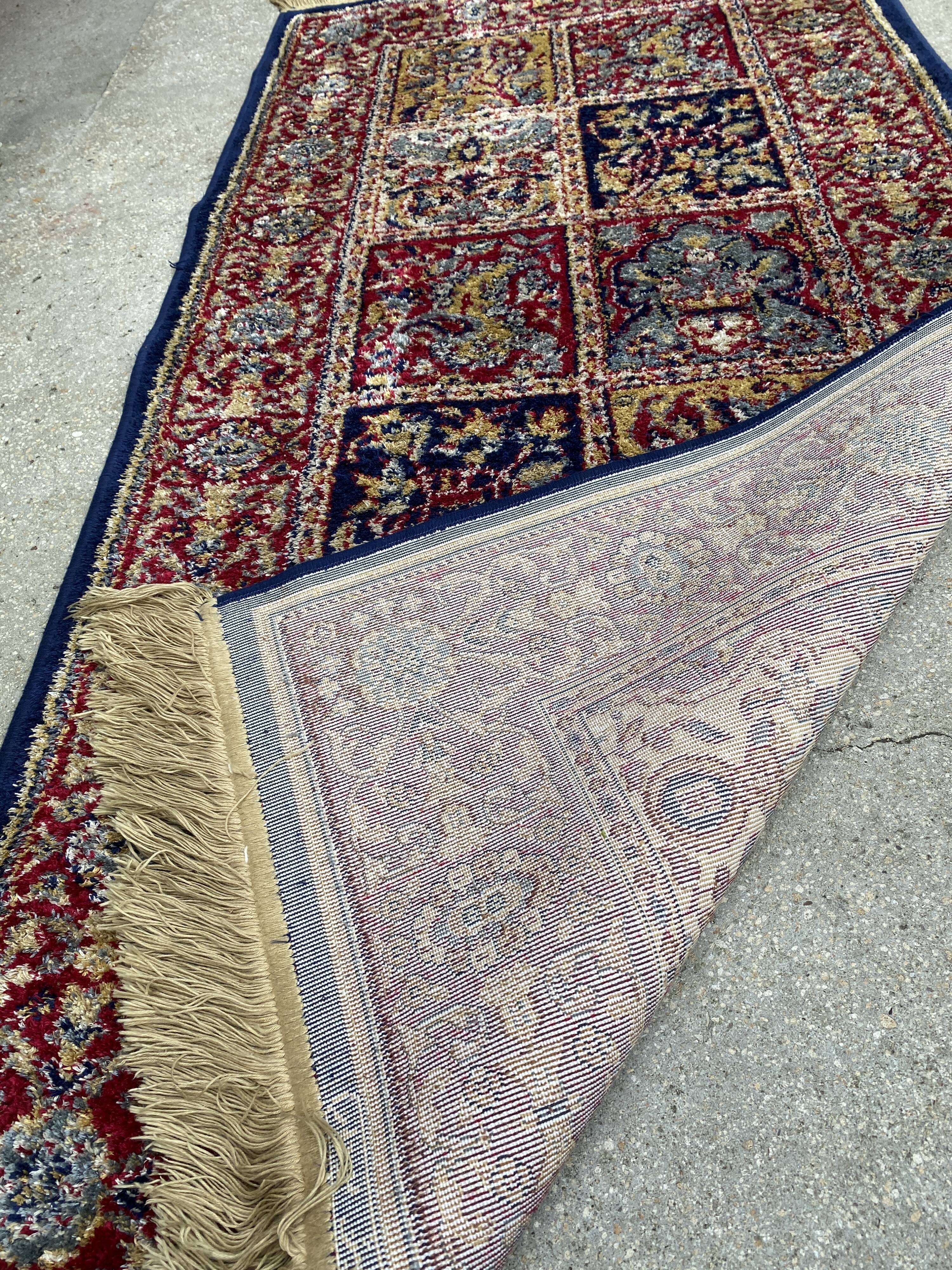 Vintage mechanical Turkish rug with box decoration on a red and navy blue background 139 x 68 cm