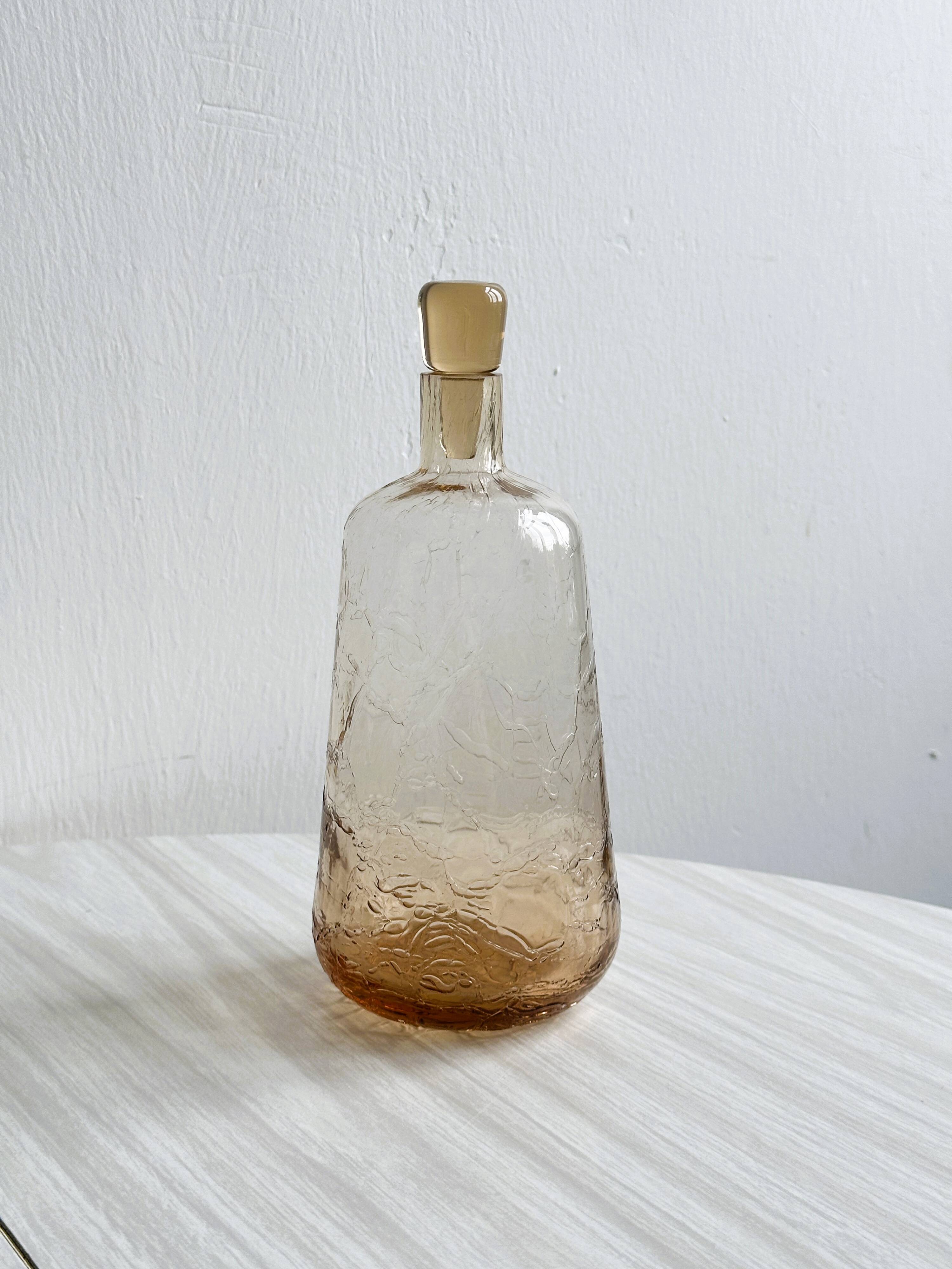 Translucent pinkish iridescent cracked glass bottle.