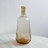 Translucent pinkish iridescent cracked glass bottle.