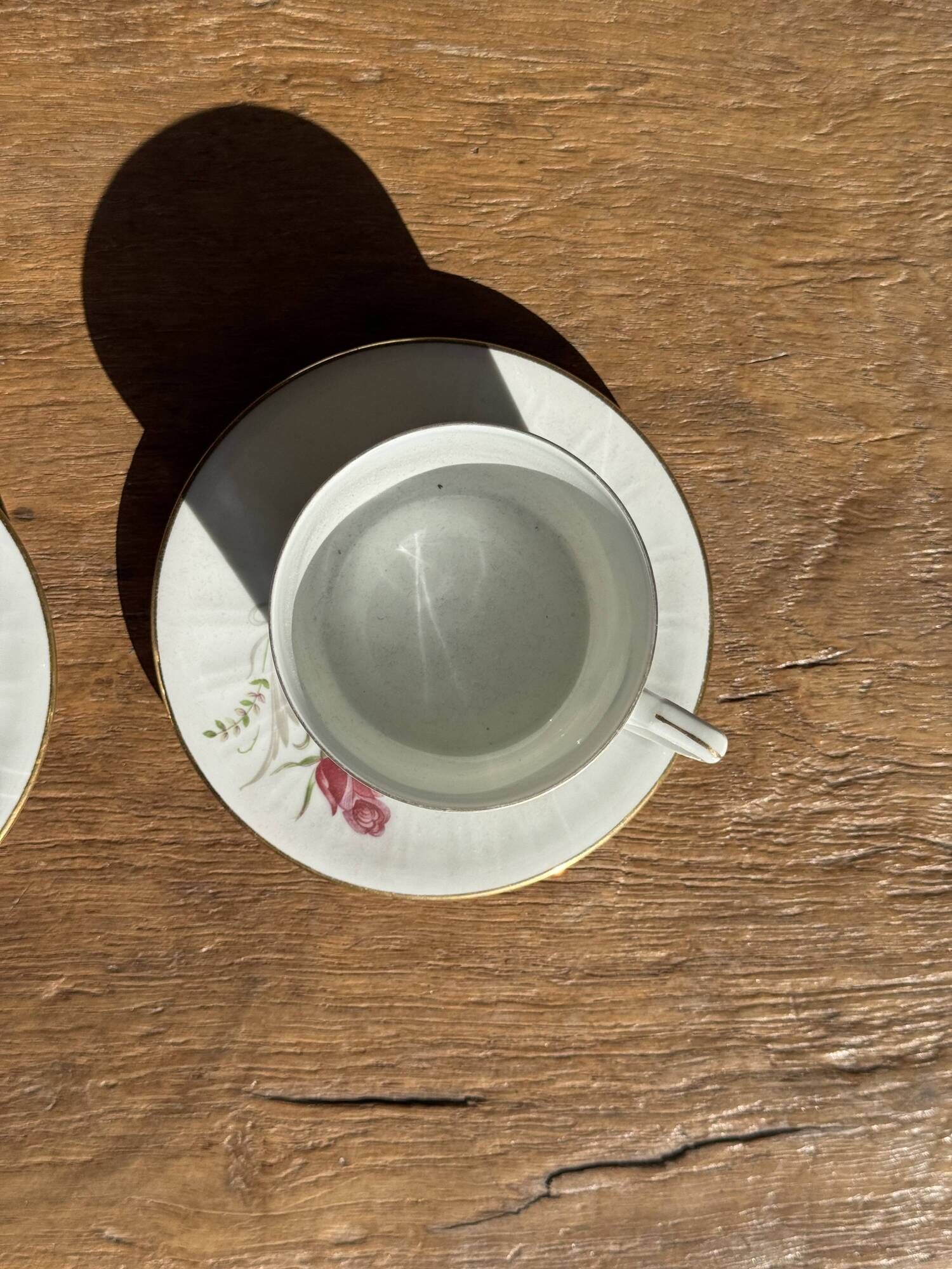 Pair of white porcelain cups from ADP France with a floral pattern and their s