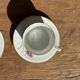 Pair of white porcelain cups from ADP France with a floral pattern and their s