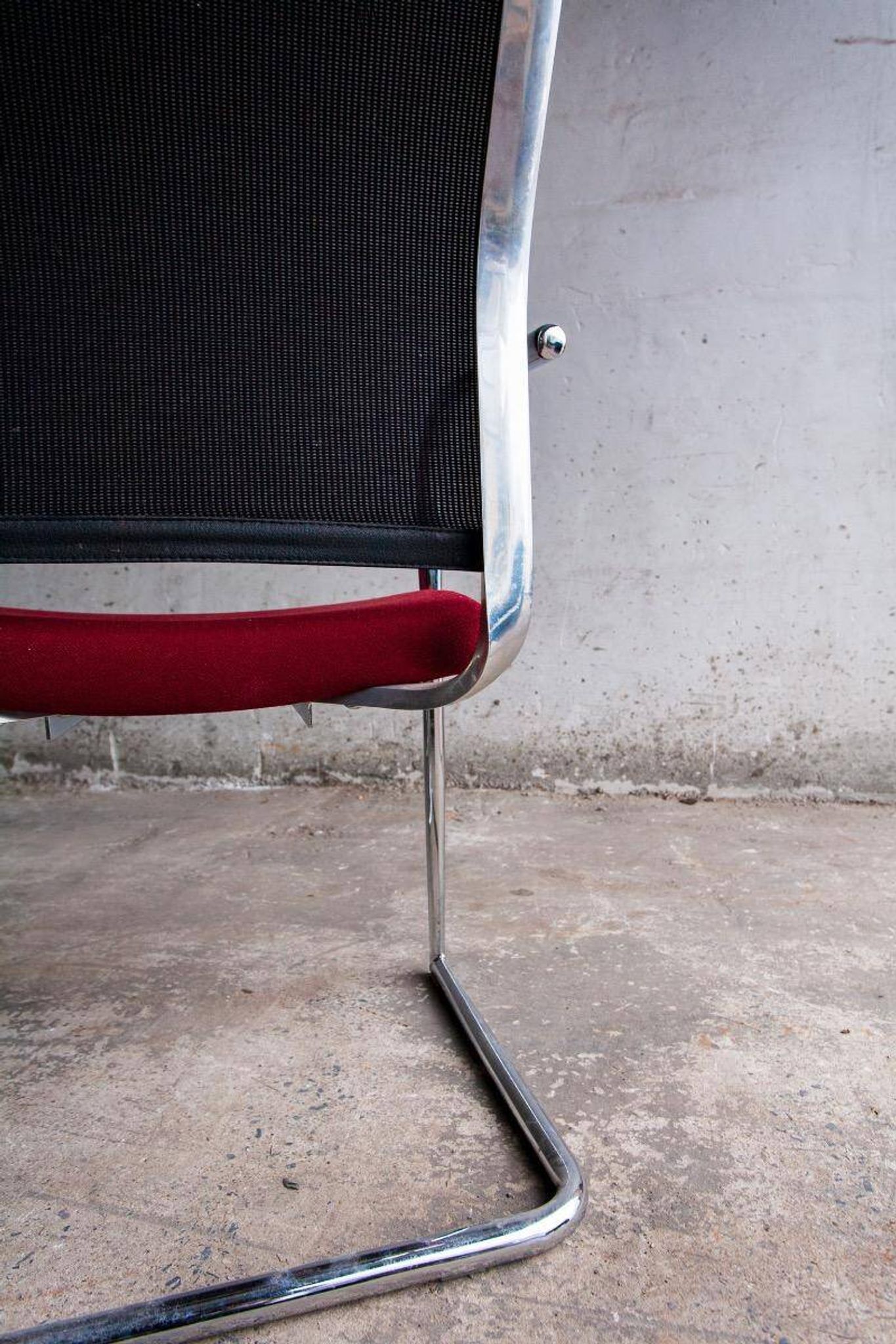 Set of 4 cantilever chairs with burgundy seat and mesh backrest.