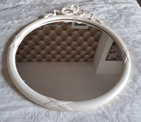 Miroir rond en bois sculpté avec en haut un ruban formant un noeud coloris crème