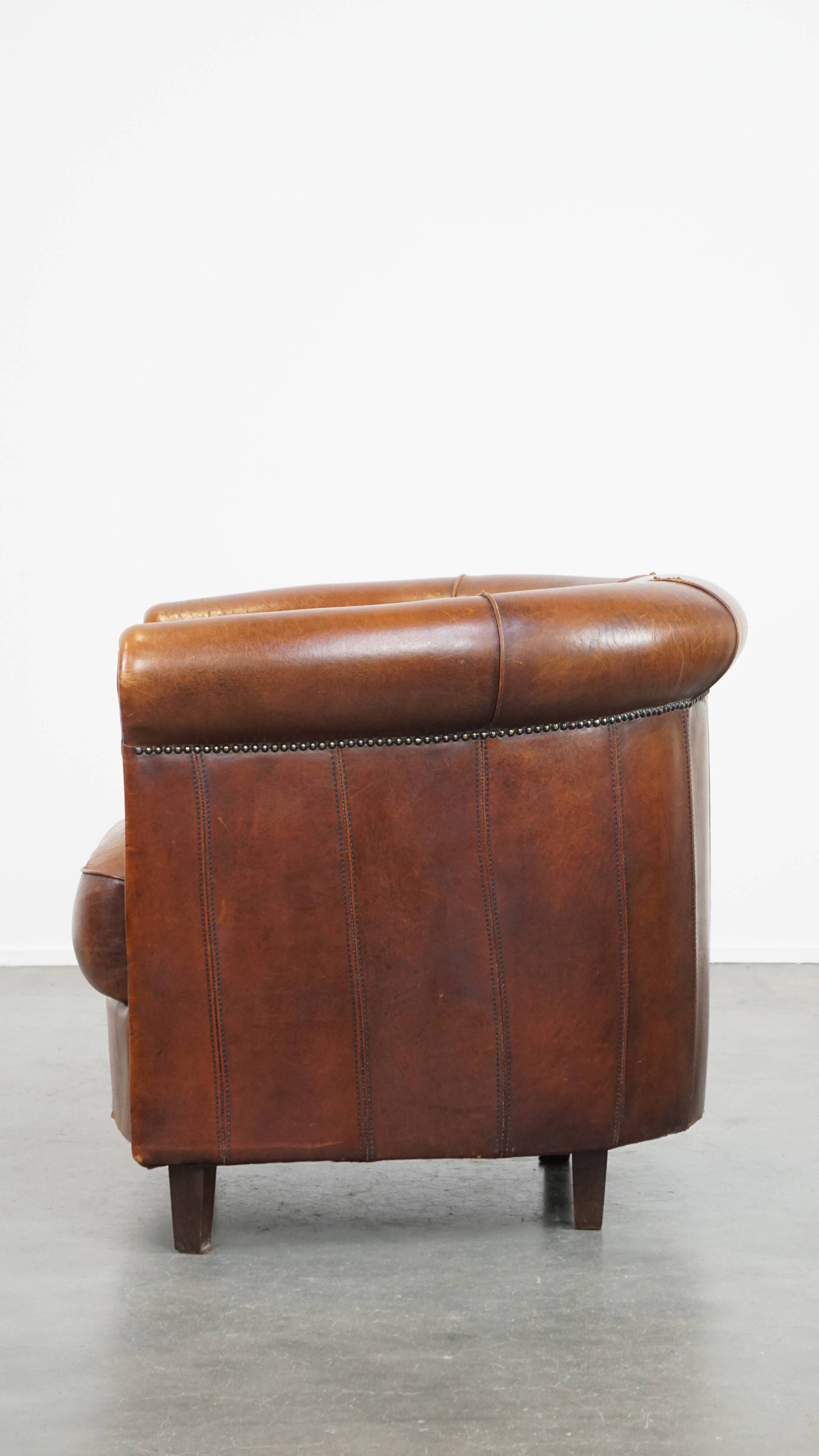 Sheep leather club chair in a cognac color and finished with piping