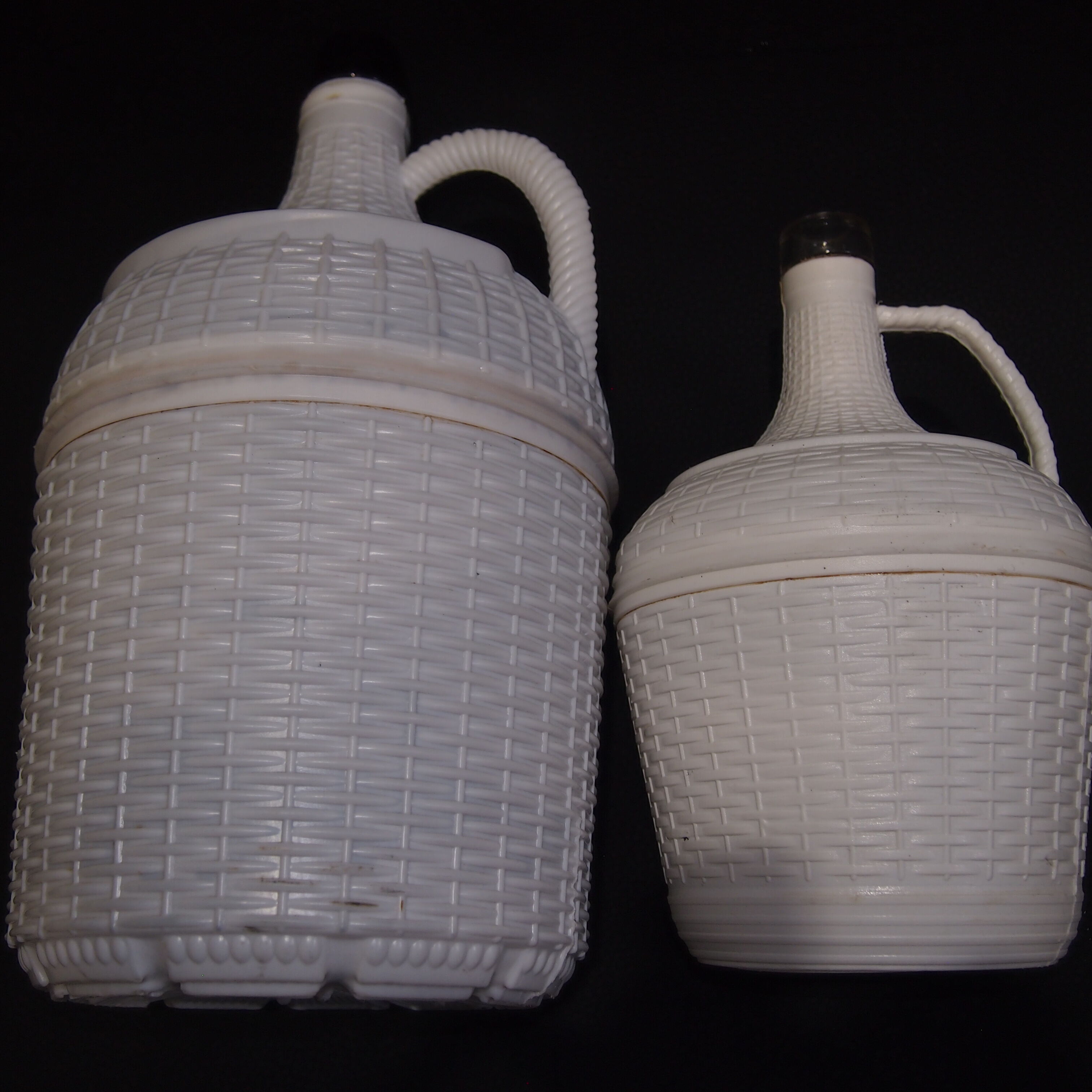 Pair of white covered demijohns