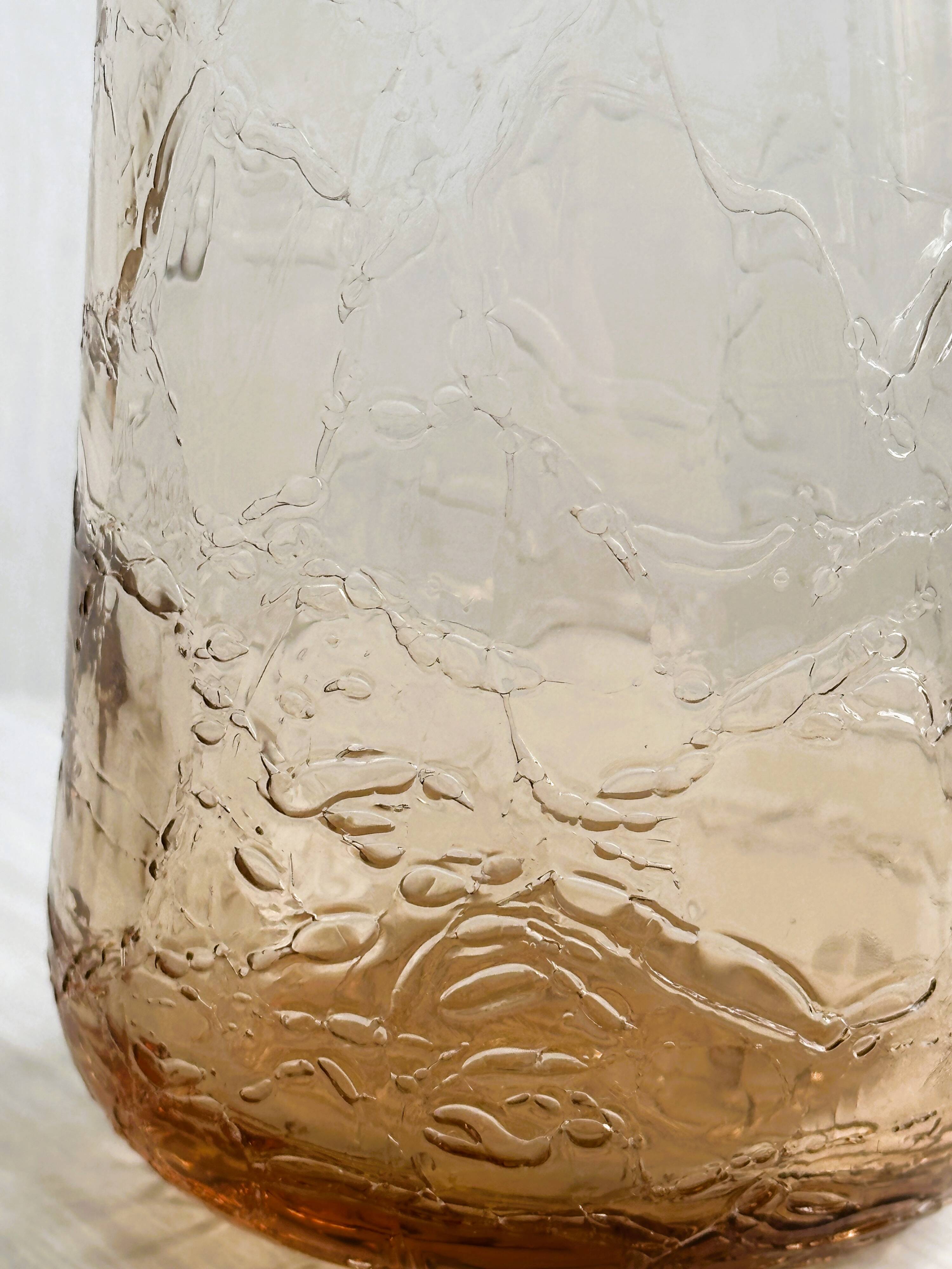 Translucent pinkish iridescent cracked glass bottle.