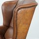 Fauteuil à oreilles de style anglais couleur cognac en cuir de vache.