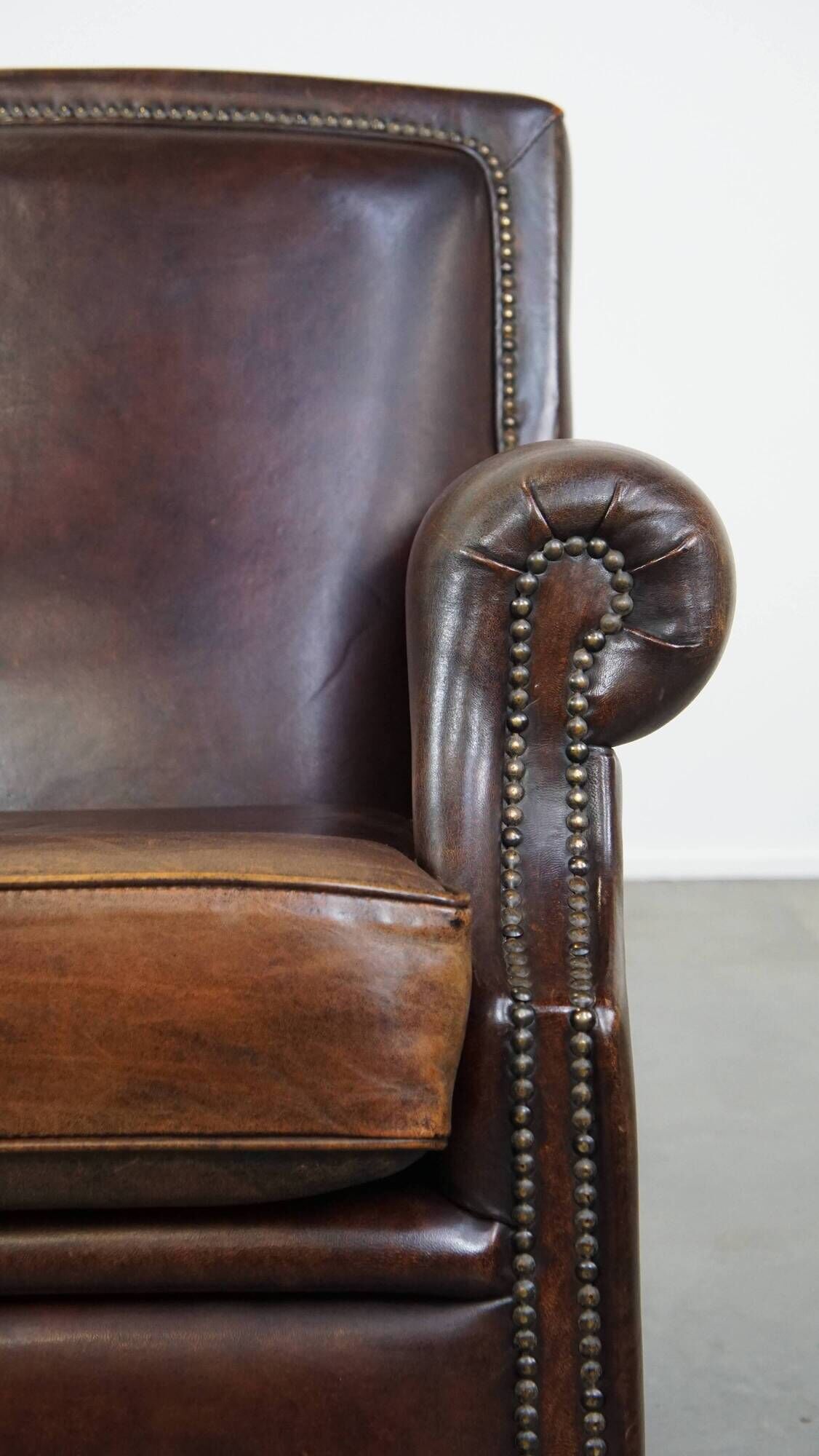 Dark brown sheepskin armchair finished with decorative nails