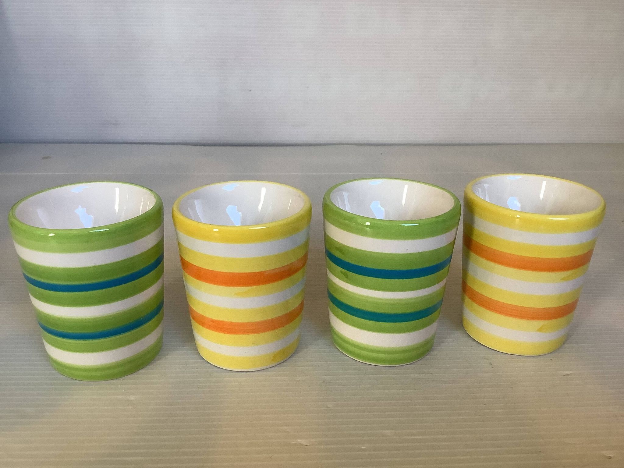 Four striped egg cups in yellow and green.
