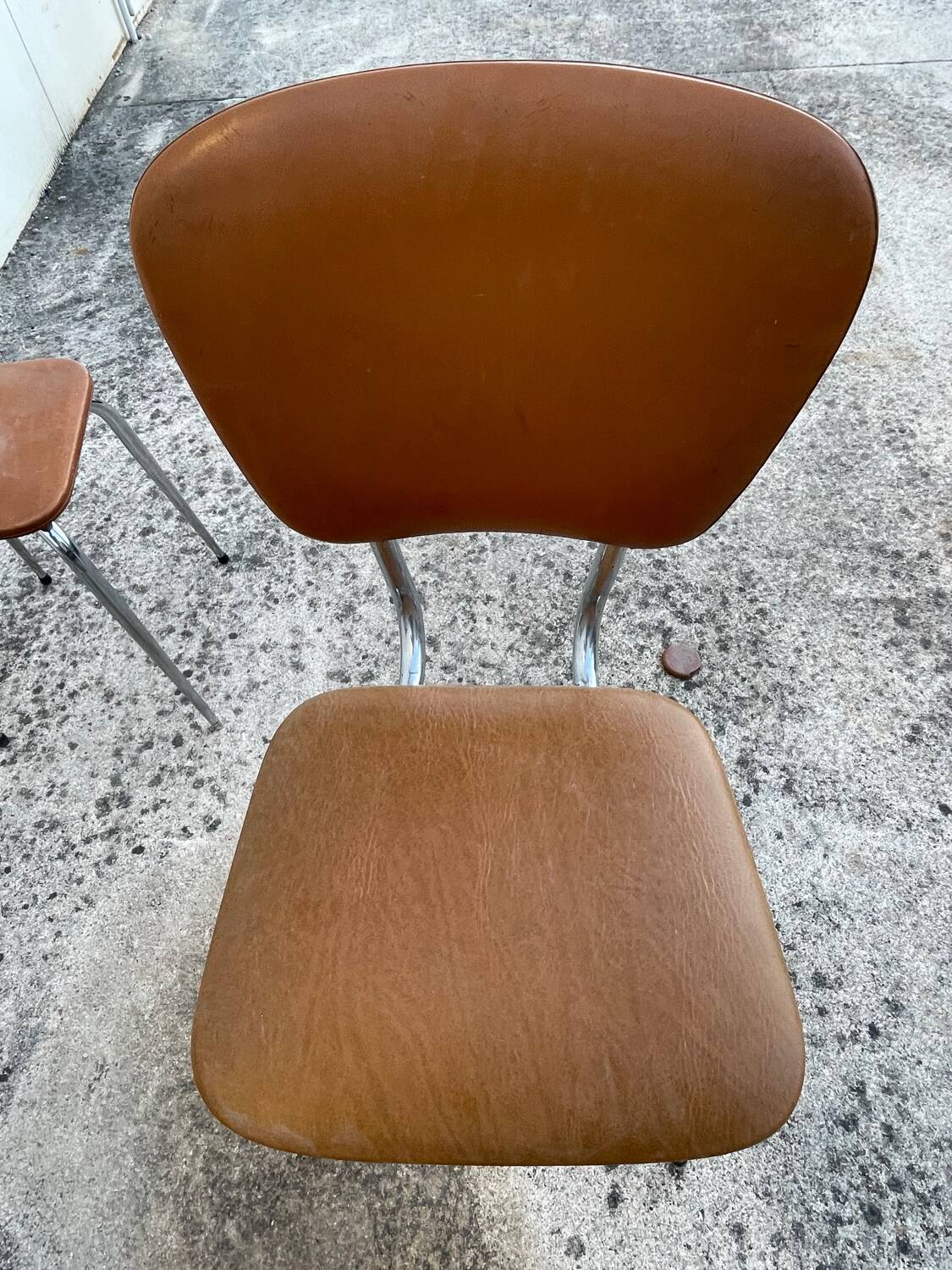 3 chairs and a vintage stool in faux leather and tubular design.