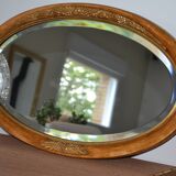 Old oval beveled wooden mirror, partly gilded and carved