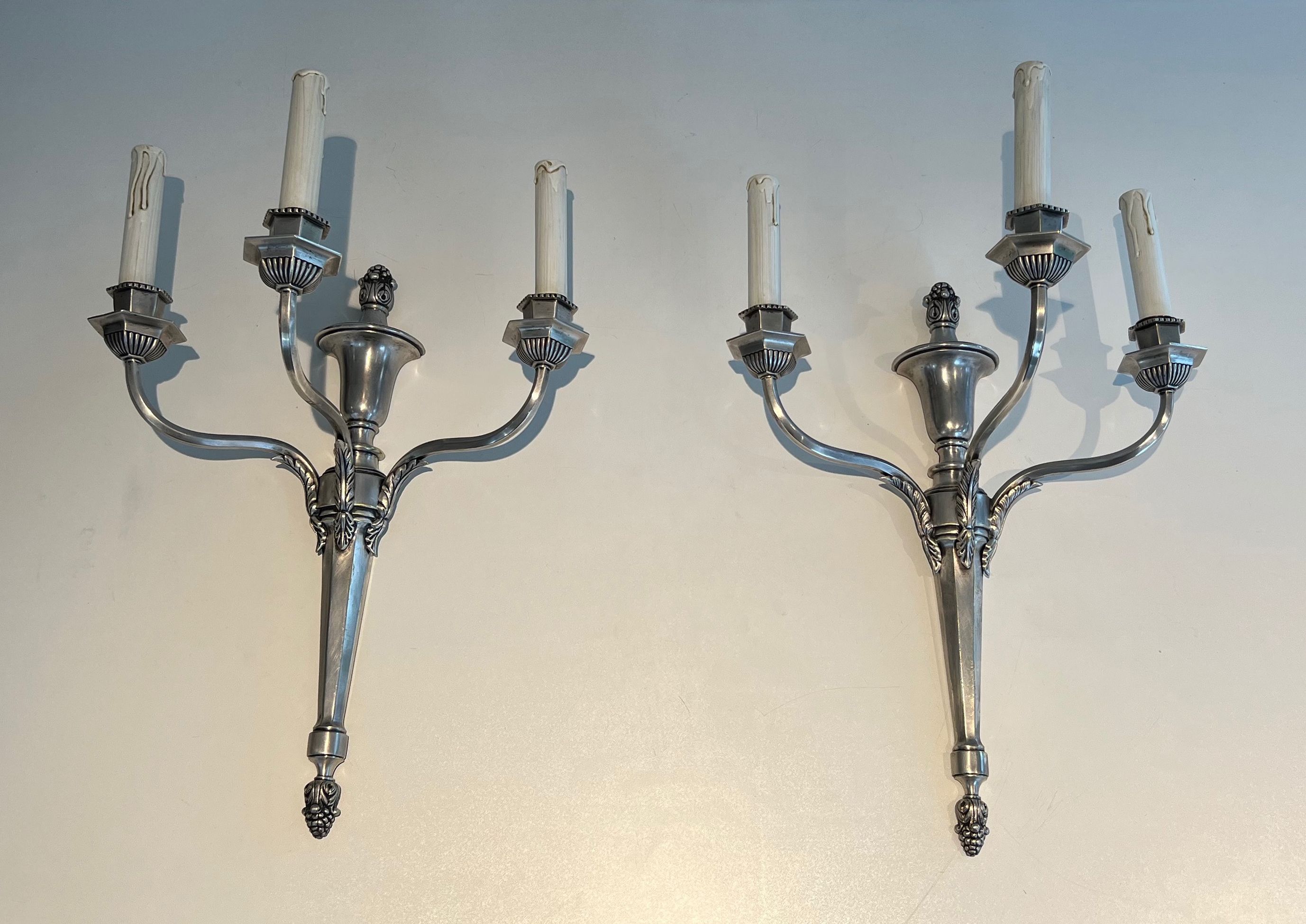 A pair of important Louis XVI style silver-plated wall sconces with three light arms.