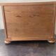 Blonde wooden doll's chest with brass handles.