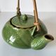 Vintage green teapot with lotus decoration and bamboo handle.