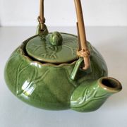 Vintage green teapot with lotus decoration and bamboo handle.