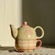 Vintage porcelain teapot and cup set with pink and beige floral and gingham pattern