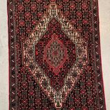 Ancient Persian carpet, wool, red tones, hand-knotted.