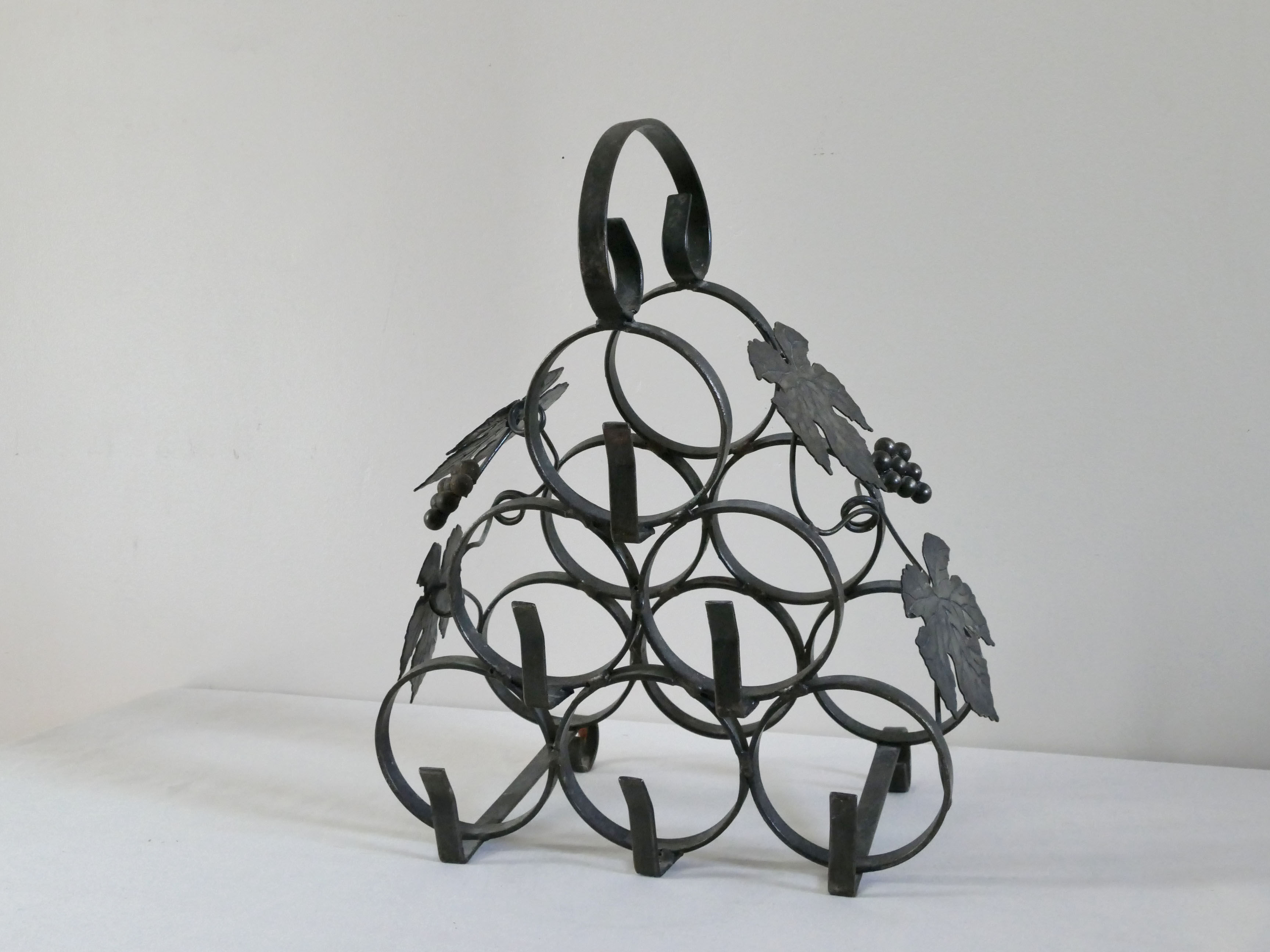 Vintage black wrought iron bottle holder decorated with vine leaves