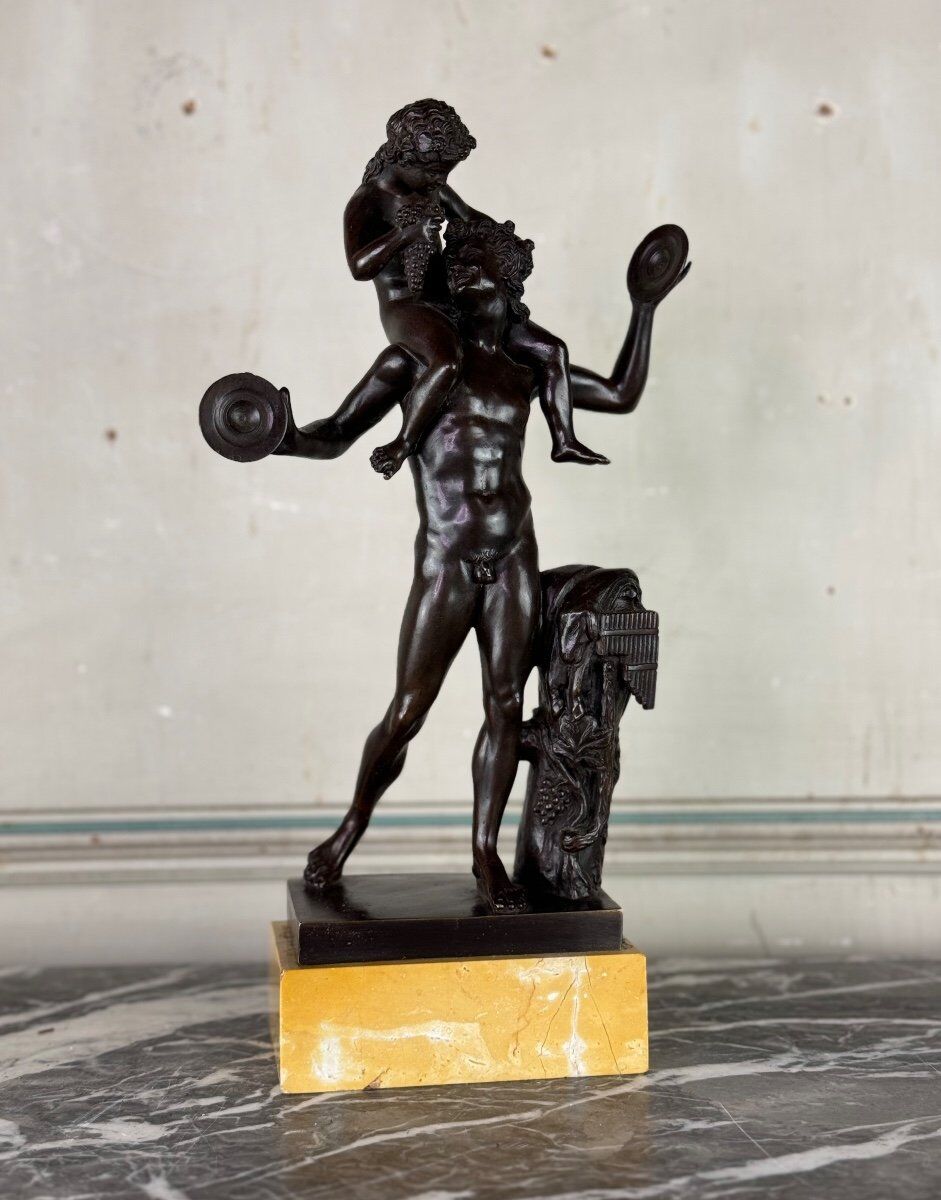 Dionysus on the shoulders of a satyr, bronze after the antique on a yellow Siena base.