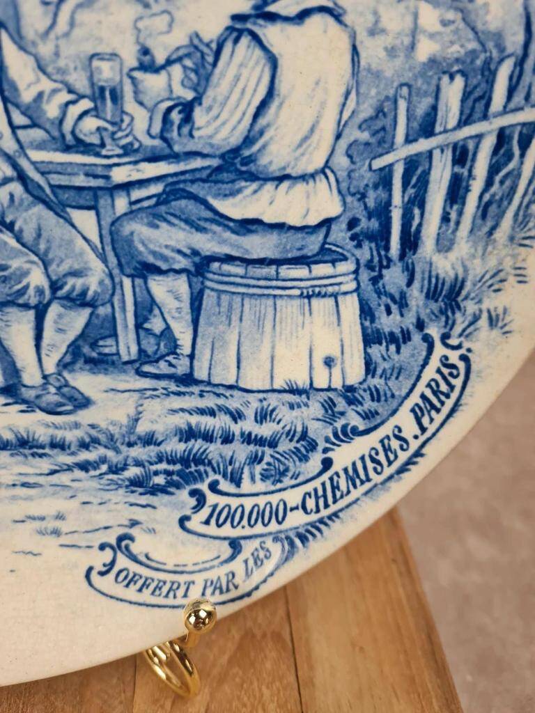 Old advertising plate with blue decoration after Teniers – 100,000 Shirts Paris