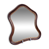 Antique wall mirror in carved wood with a wavy shape and a golden trim.