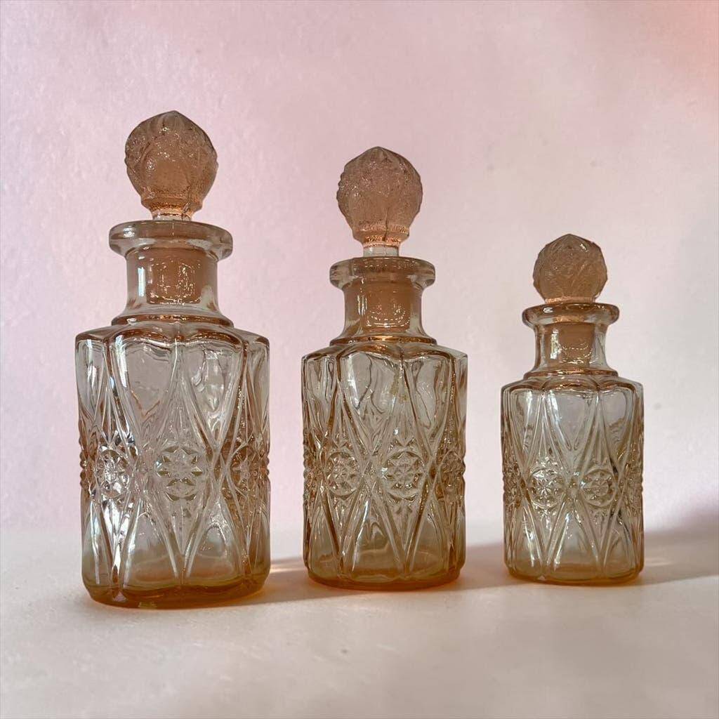 Set of 3 vintage pink glass bottles with corks.