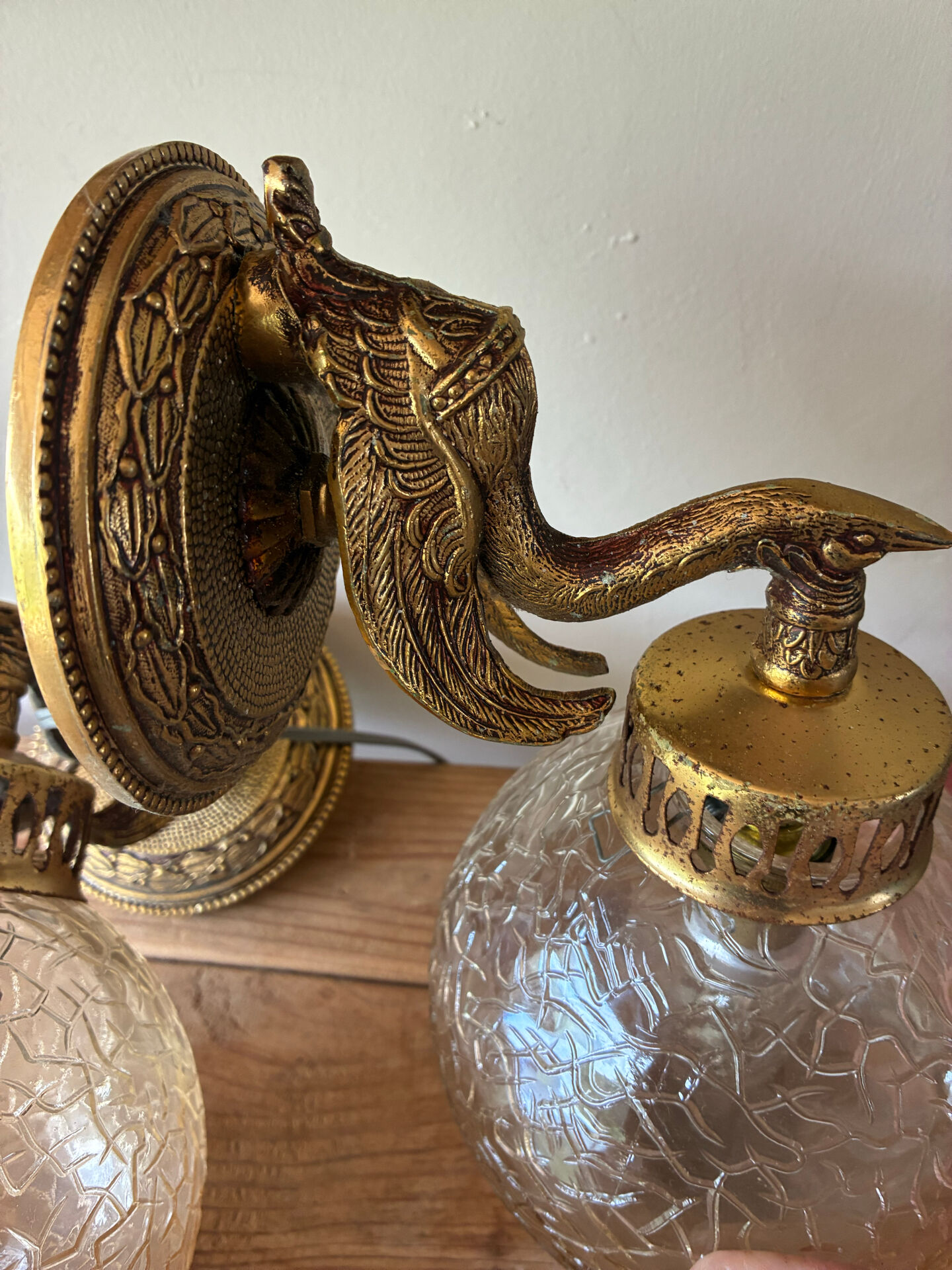 Pair of vintage wall sconces with golden metal swan heads and glass.
