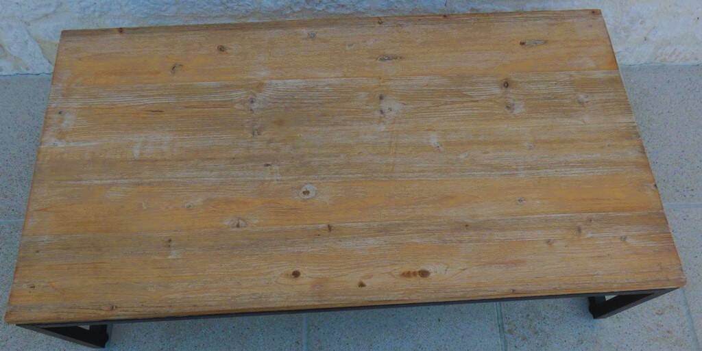 Industrial style coffee table with wooden top supported by a metal base -