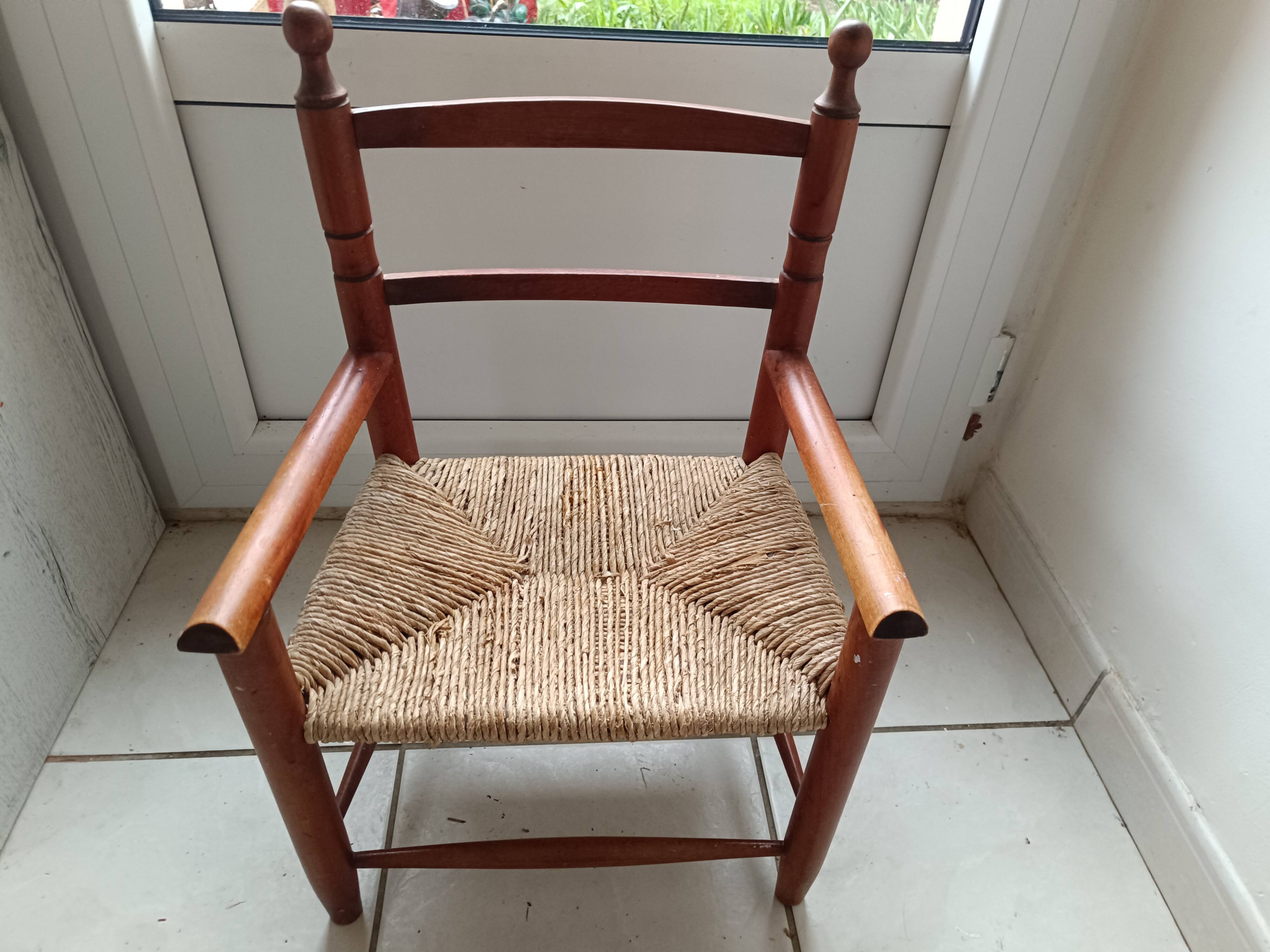 Children's wooden armchair and straw-covered seat.