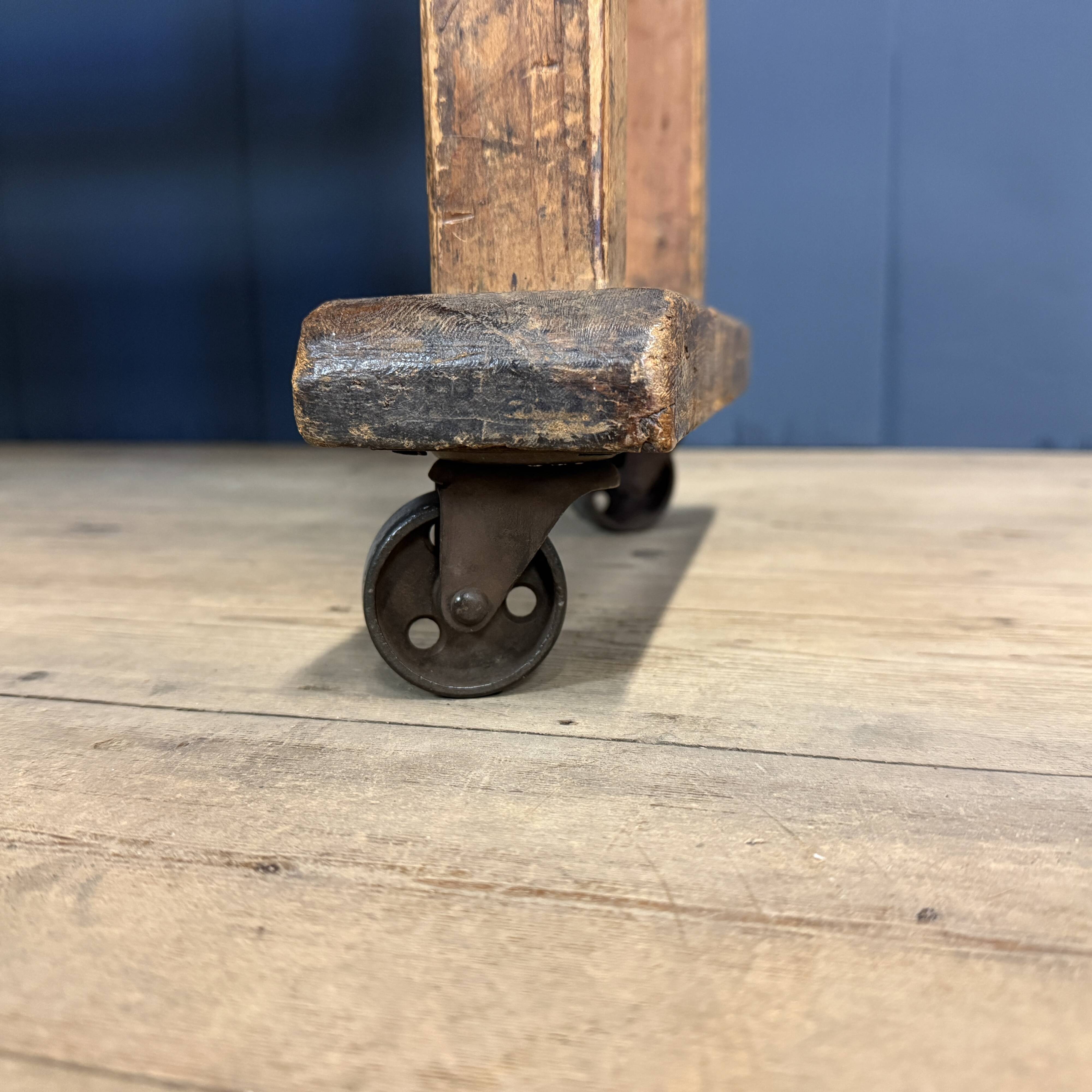 Old wooden workshop shelf with cast iron wheels.