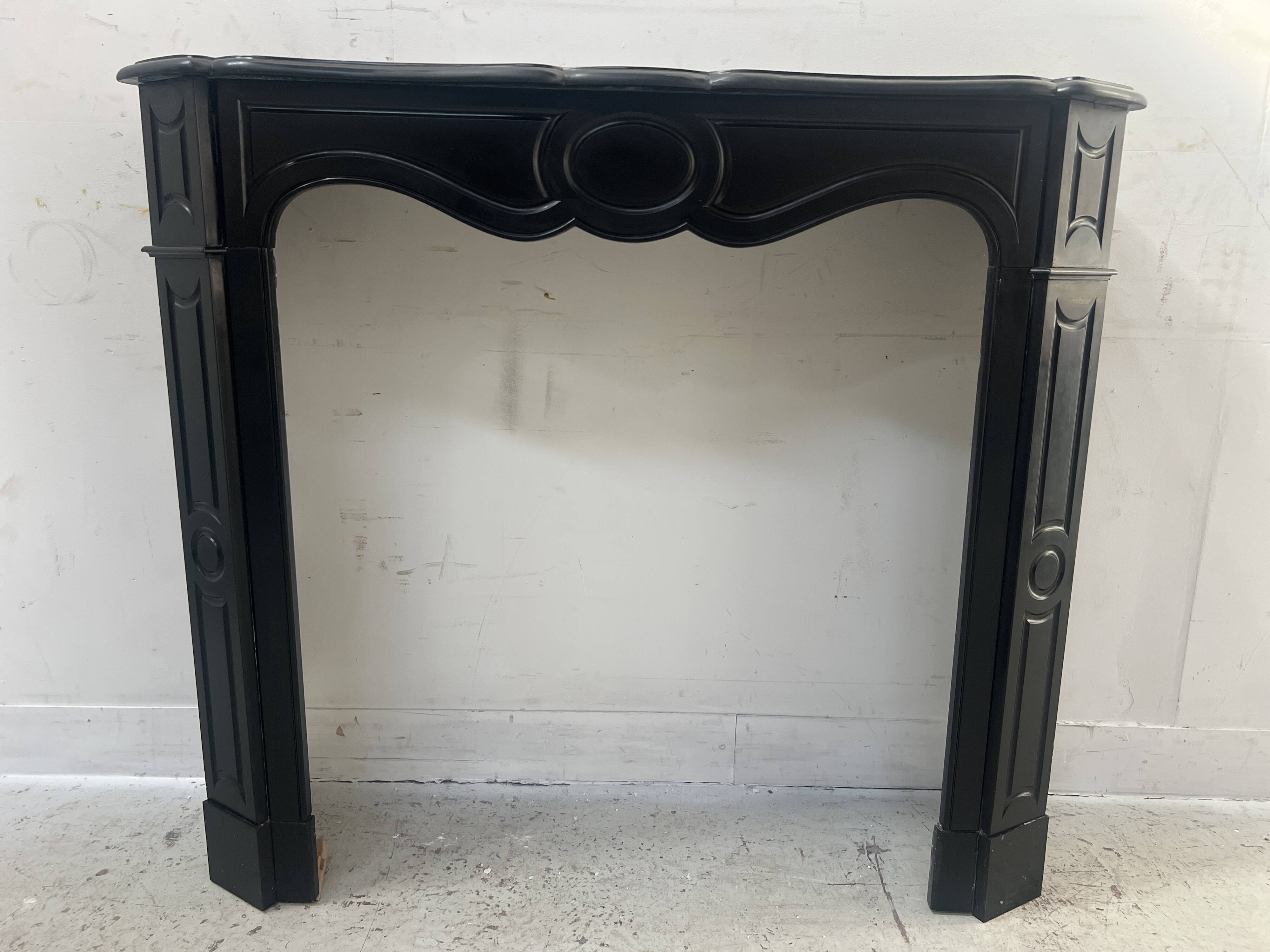 Cheminée de style Louis XV modèle Pompadour en marbre noir moucheté, XXe siècle