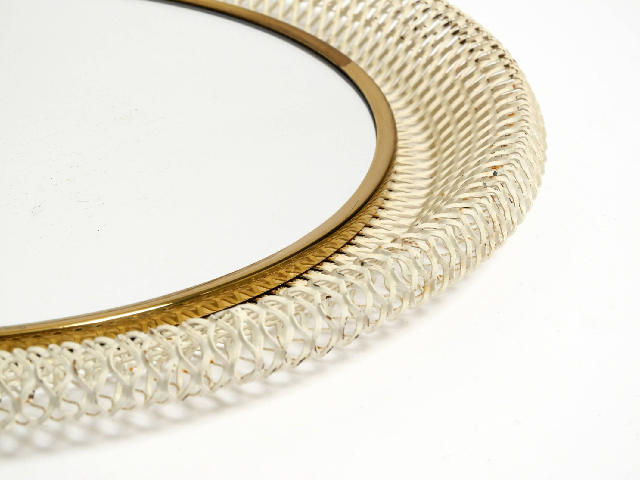 Mid Century Modern round wall mirror with a white expanded metal frame