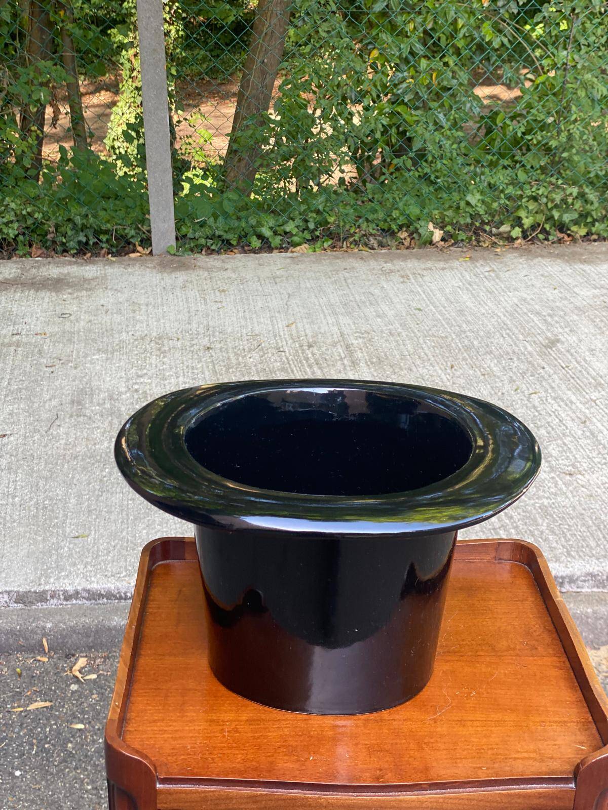 A black top hat-shaped vale turned upside down from the 1960s.
