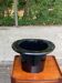 A black top hat-shaped vale turned upside down from the 1960s.