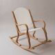 Handcrafted rocking chair in curved wood with a white seat.