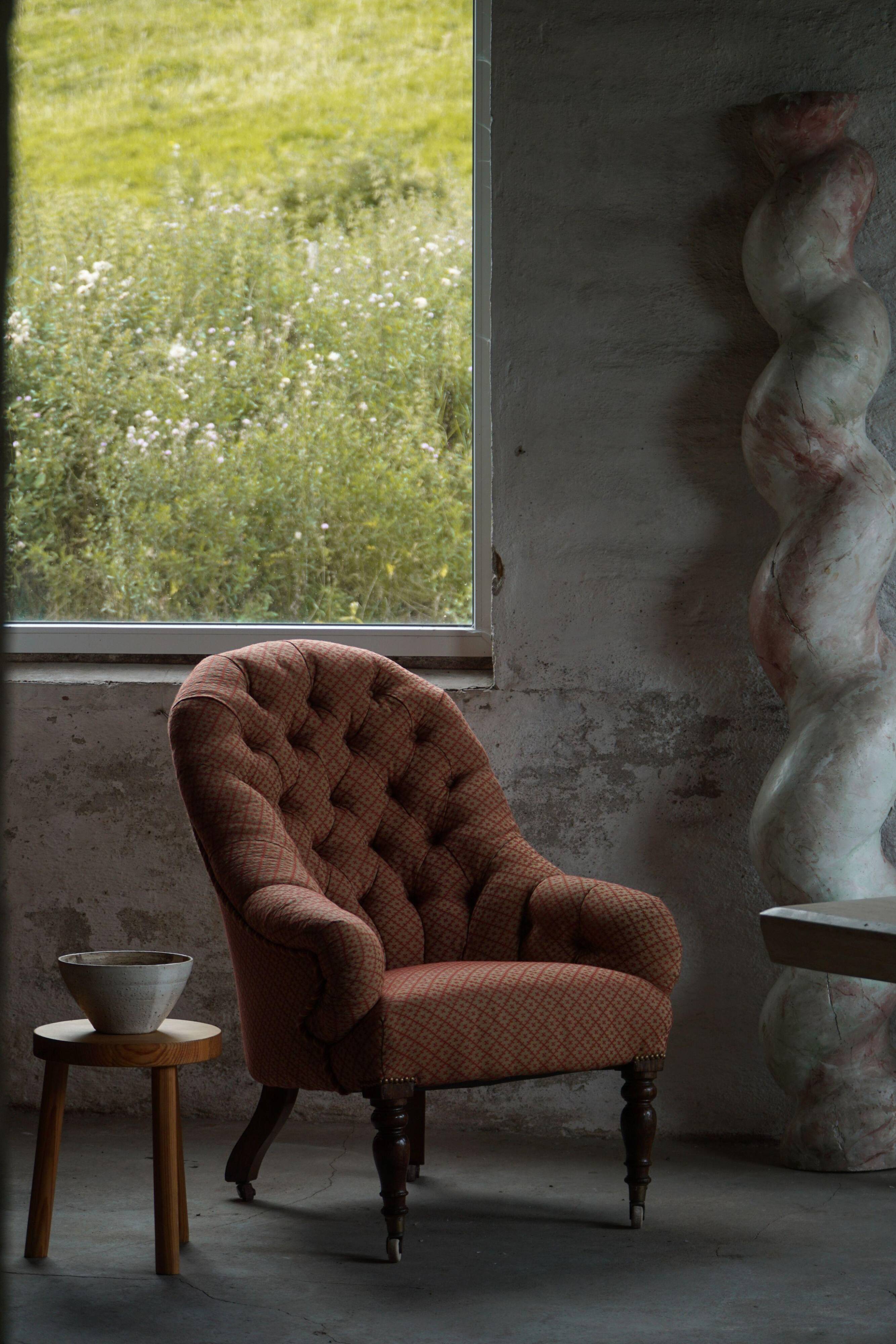 Victorian mahogany armchair, with wheels and coloured fabric, England, early 1900s.