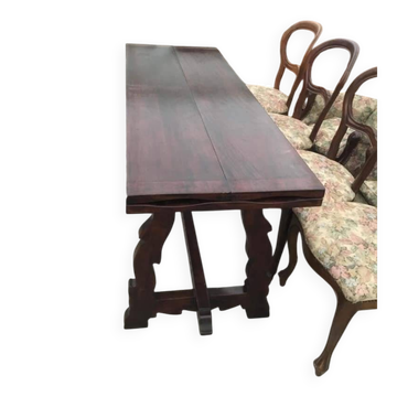 19th-century brown walnut dining table with sculpted trestle legs.