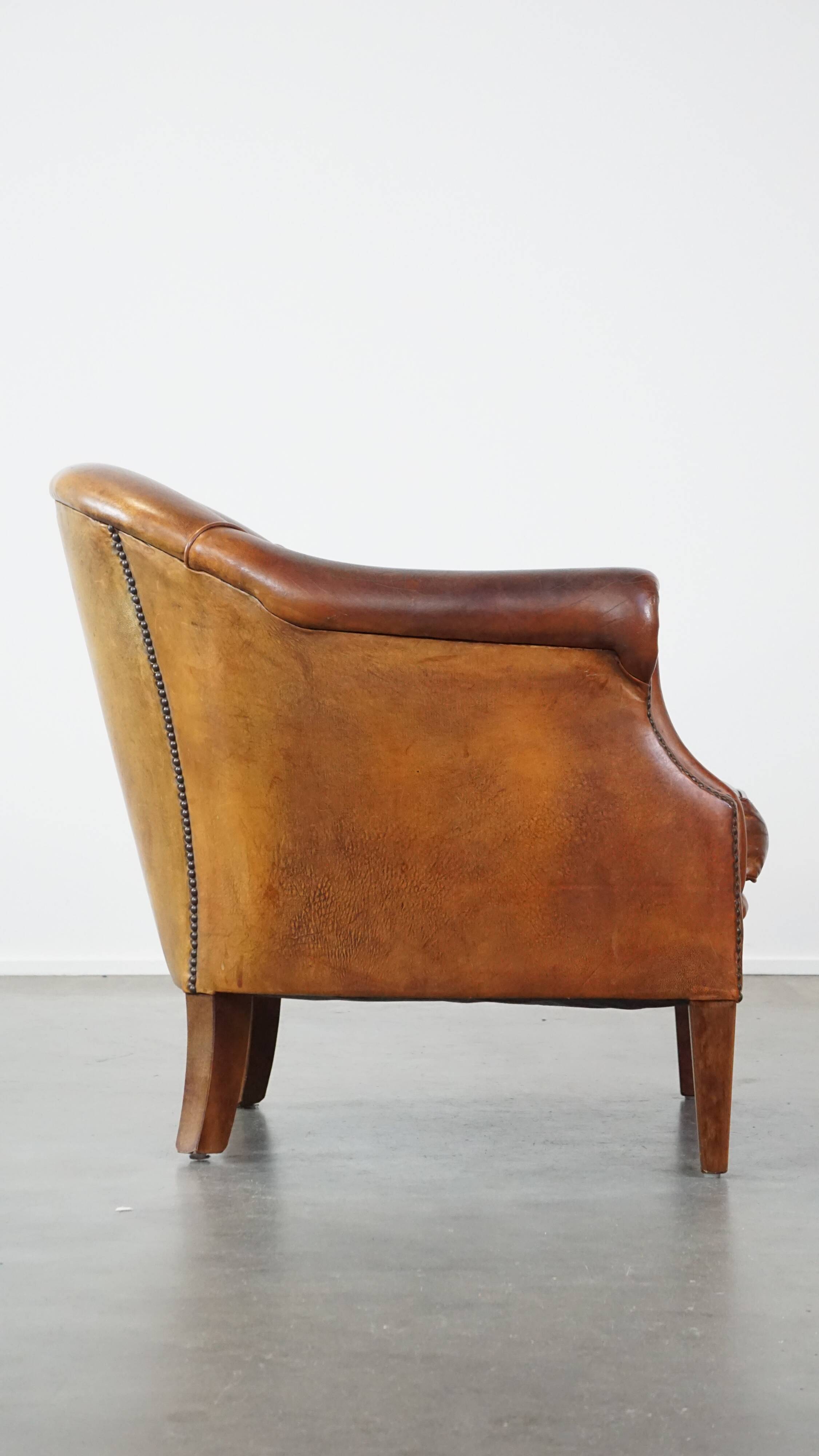 Un fauteuil club robuste mais confortable en cuir de mouton et fini avec des clous décoratifs