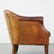 Un fauteuil club robuste mais confortable en cuir de mouton et fini avec des clous décoratifs