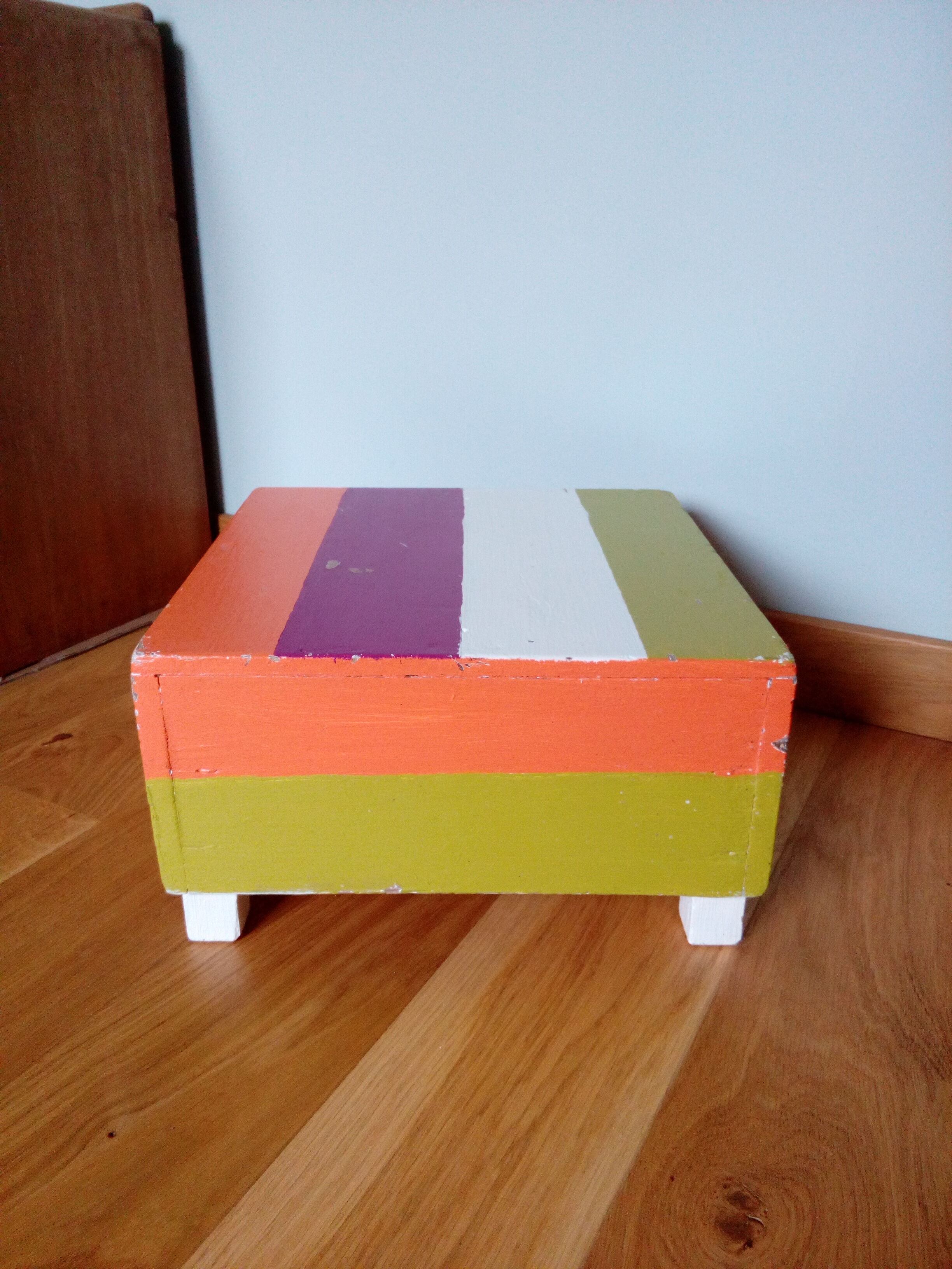 Low wooden stool painted in bright colours
