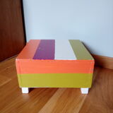 Low wooden stool painted in bright colours