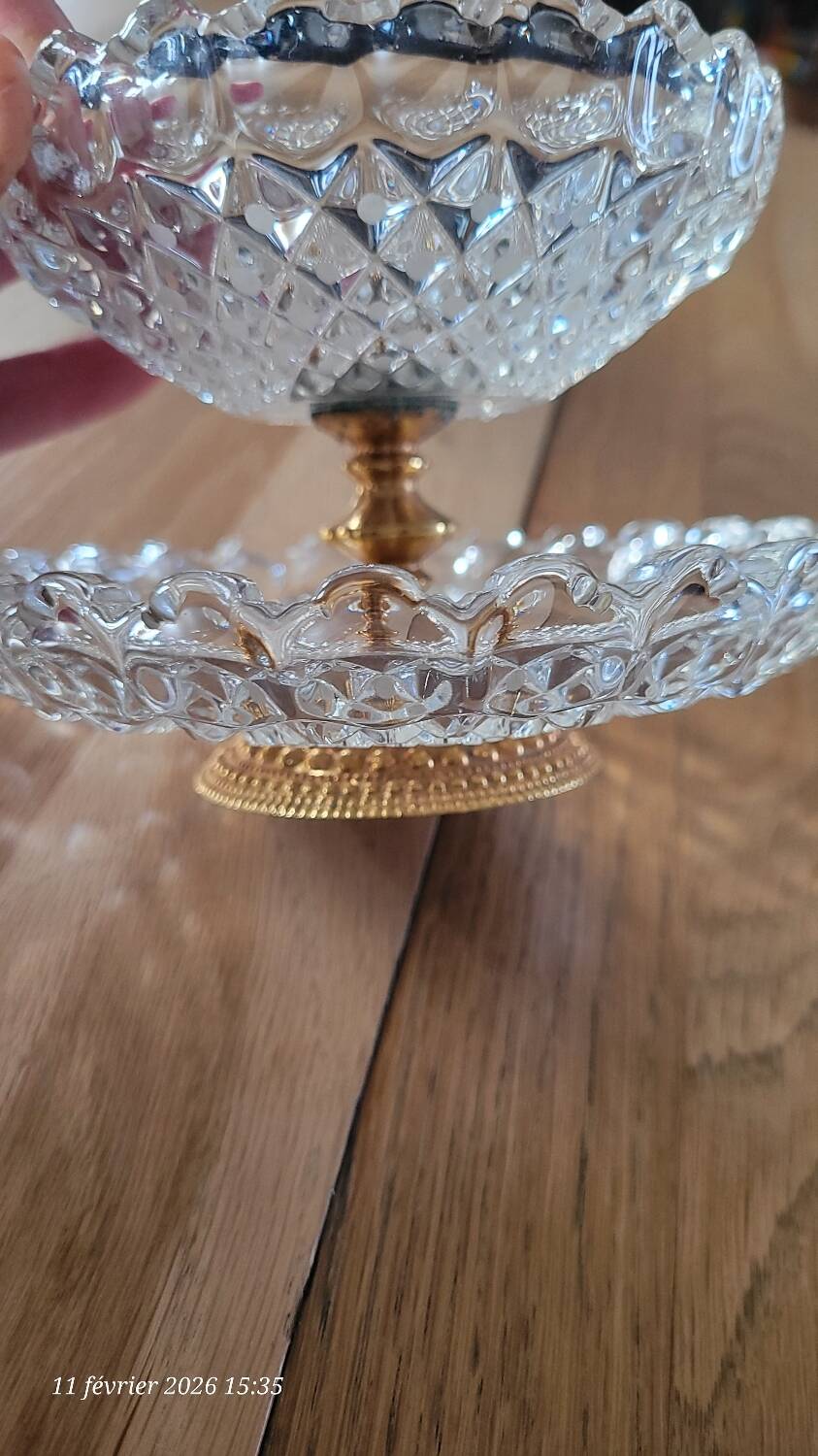 Two-tier display stand in cut glass mounted on a gold metal base.