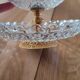 Two-tier display stand in cut glass mounted on a gold metal base.