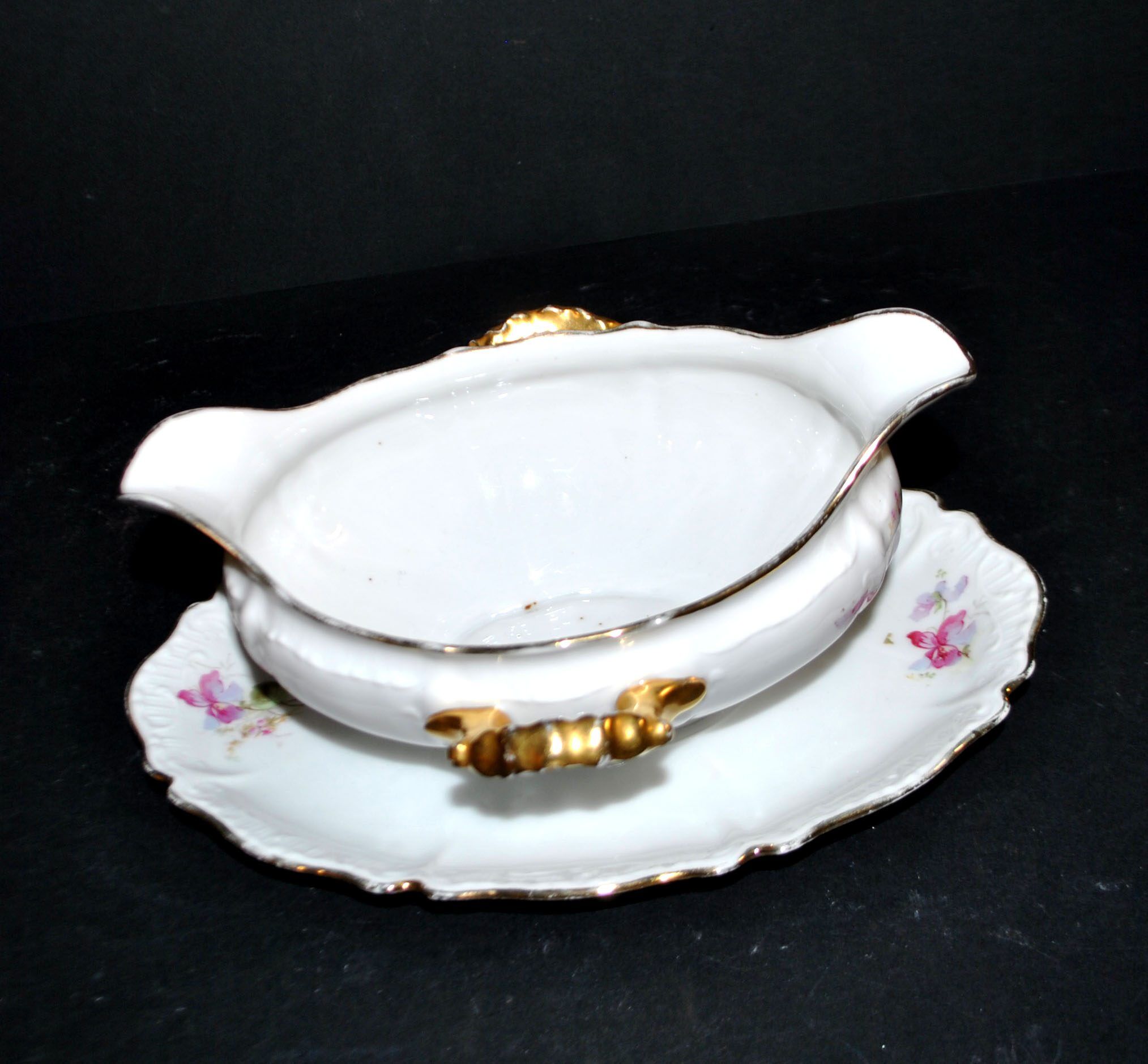 Vintage pouring sauce boat in floral porcelain with gilding.