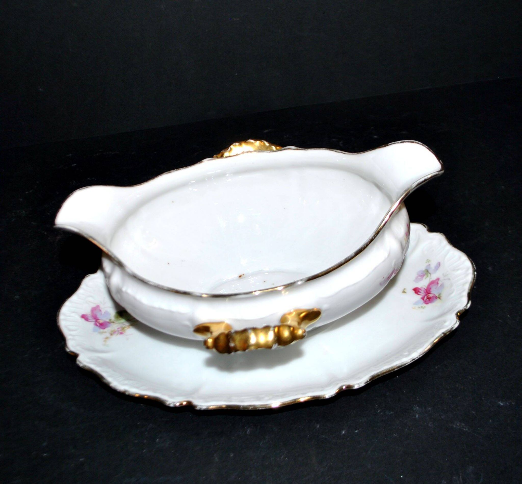 Vintage pouring sauce boat in floral porcelain with gilding.