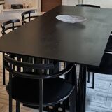 Table de salle à manger noire, en bois, rectangle avec chaises rembourrées.