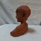 Terracotta bust of a smiling little boy.